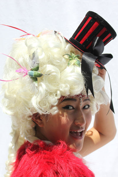 Our model is wearing the Red and Black Ringleader Mini Top Hat.